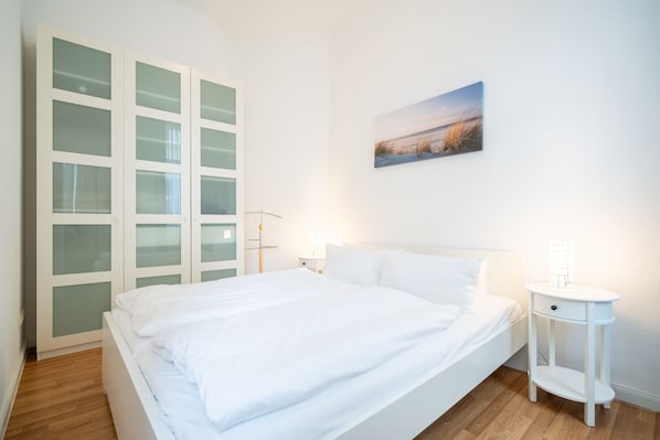 Un dormitorio con cama, mesita de noche, un cuadro en la pared y un armario empotrado con puertas de cristal.