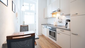 Une cuisine moderne avec des armoires blanches, des appareils en acier inoxydable et un coin repas comprenant une table et des chaises.