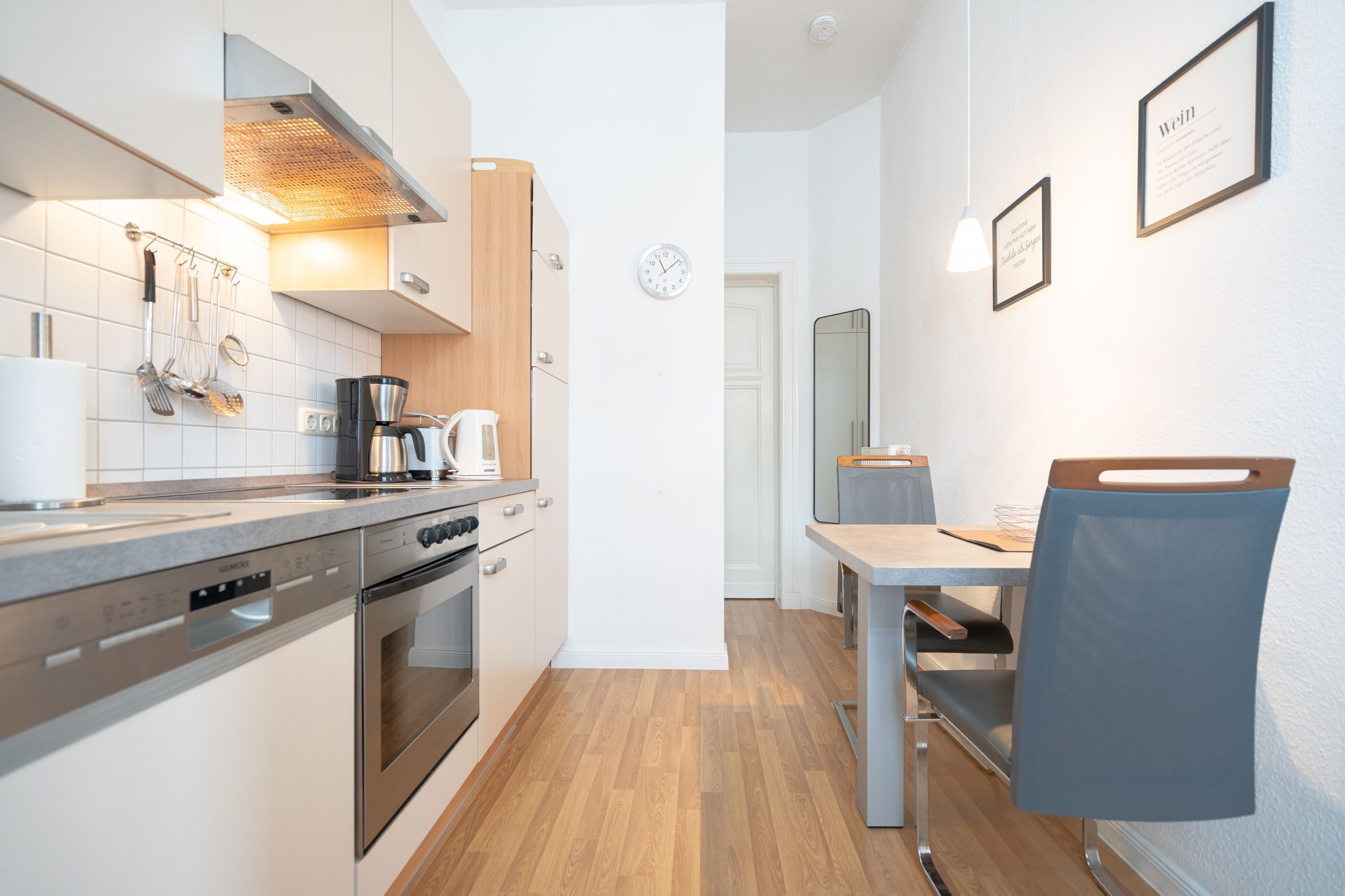 Una cucina moderna con elettrodomestici in acciaio inossidabile, un piano di lavoro in legno e un'area pranzo con tavolo e sedia.