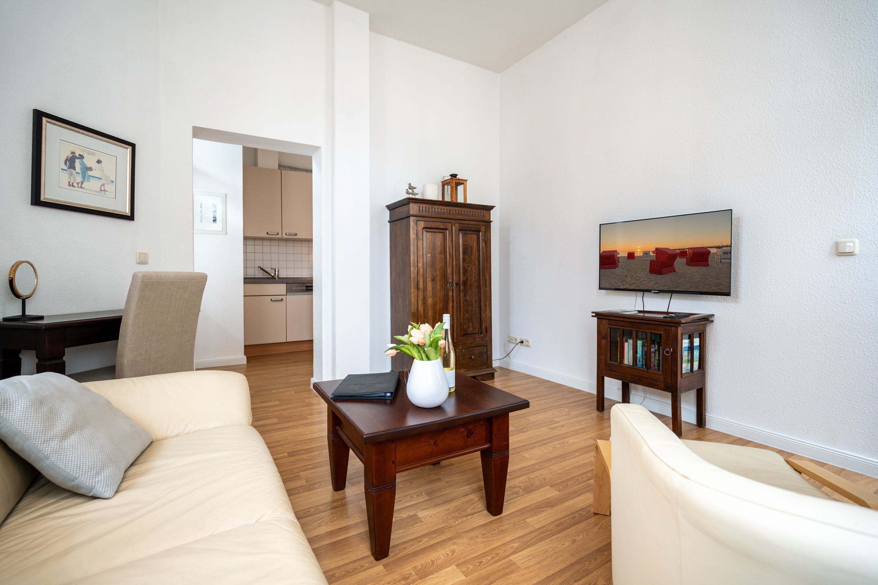A living room with a sofa, a coffee table with a vase, a television, and a wooden cabinet.