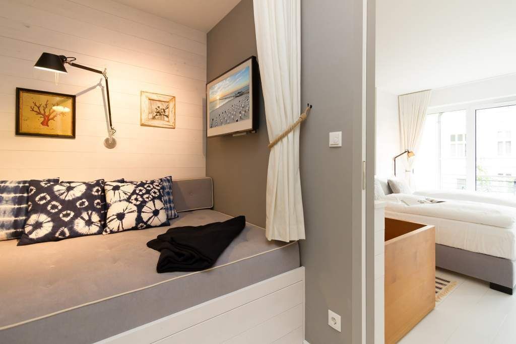 A modern bedroom with a bed, a sofa, a desk, and a window.