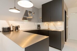A modern kitchen with a central island, pendant lighting, and built-in appliances. - Villa Strandgrün, App. 05 (Heringsdorf)
