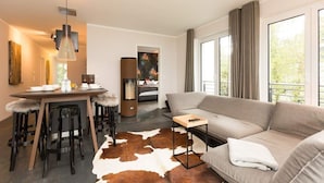 A modern living room with a sofa, a dining table with chairs, a cowhide rug, and large windows. - Villa Strandgrün, App. 06 (Heringsdorf)