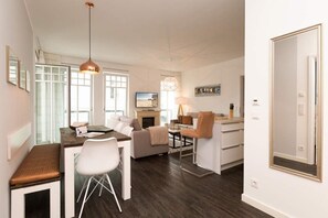 Una sala moderna con comedor, un sofá, una mesa de centro y un televisor.