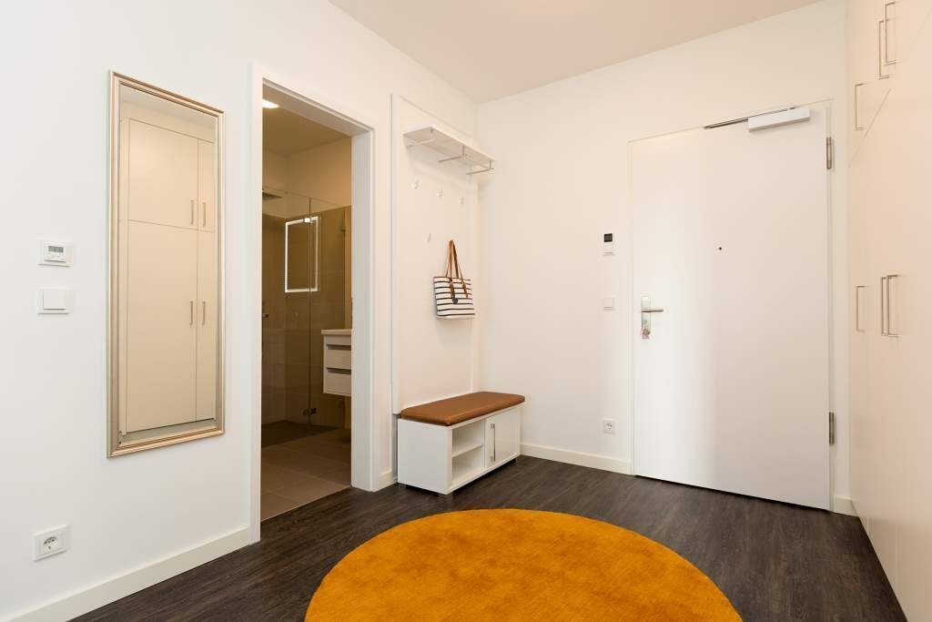 A hallway with a bench, a door, and a mirror.