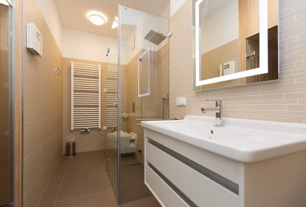 Ein modernes Badezimmer mit einer Glasdusche, einem weißen Waschbecken und einem großen Spiegel.