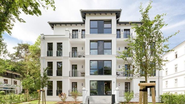 A multi-story residential building with a central entrance, balconies, and a well-maintained garden. - Villa Strandgrün, App. 02 (Heringsdorf)