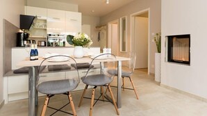 A modern kitchen with a central island, clear chairs, and a dining table. - Villa Strandgrün, App. 02 (Heringsdorf)