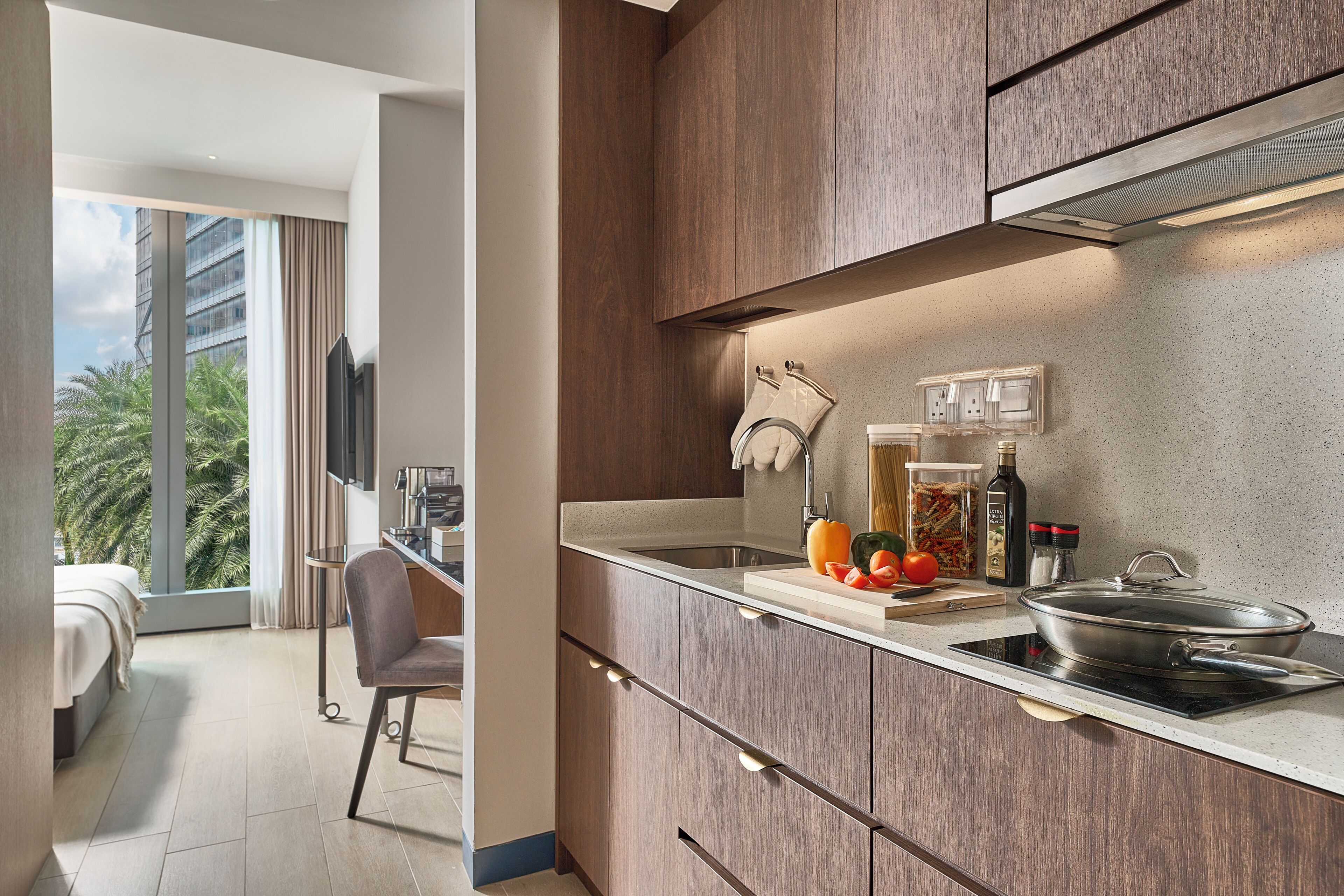 A modern kitchen with a built-in stove, a sink, and a countertop with various kitchen items.