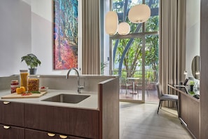 Cozinha moderna com uma janela grande, área de refeições com mesa e cadeiras, e vista para árvores lá fora.