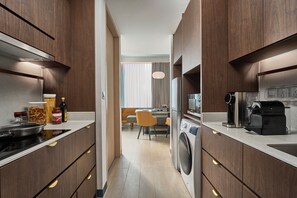 Een moderne keuken met een ingebouwde wasmachine, een koffieapparaat en een eethoek op de achtergrond.