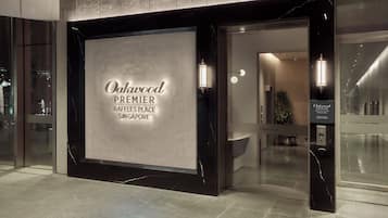 Entrada d'un hotel amb façana de marbre i un cartell que diu 'Oakwood Premier Raffles Place Singapore'.