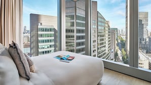 Habitación de hotel moderna con un ventanal grande, una cama y vistas a la ciudad.