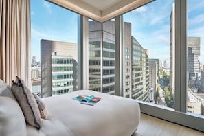 Habitación de hotel moderna con un ventanal grande, una cama y vistas a la ciudad.