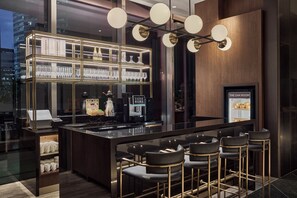 A modern bar area with a glass display case, bar stools, and a coffee machine. - Oakwood Premier Raffles Place Singapore (Singapore)