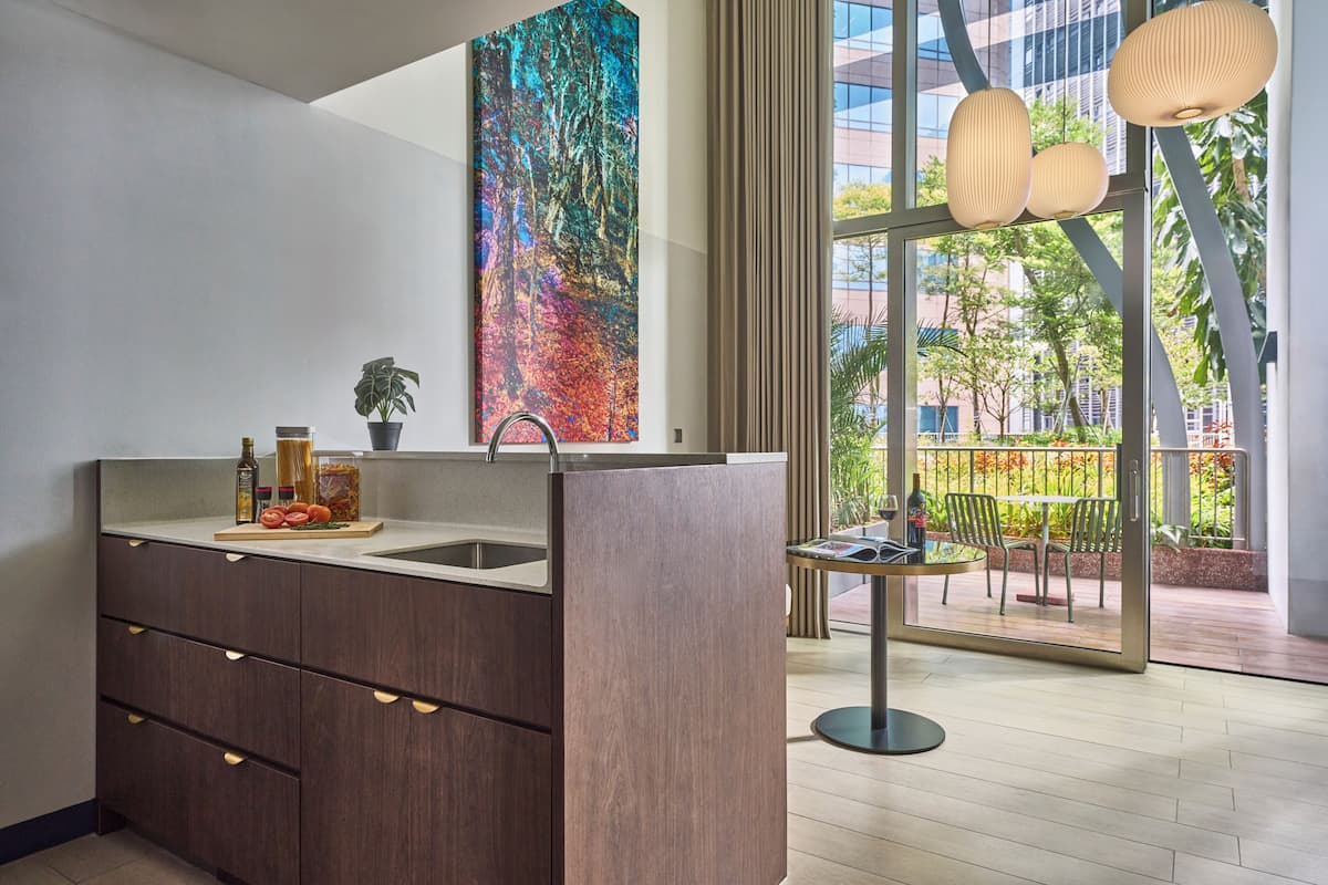 Una cocina moderna con un ventanal grande, un área de comedor con mesa y sillas, y un cuadro abstracto y colorido en la pared.