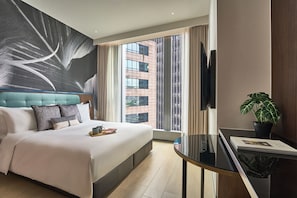 A modern hotel room with a large bed, a flat-screen TV, a dining table, and a view of a cityscape. - Oakwood Premier Raffles Place Singapore (Singapore)