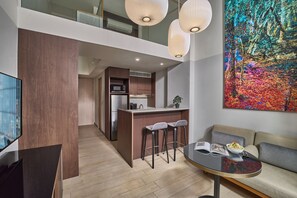 A modern kitchen with a dining area, a sofa, and a large abstract painting. - Oakwood Premier Raffles Place Singapore (Singapore)