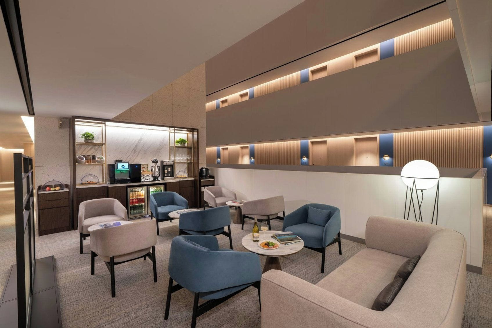 Un hall d’hôtel moderne doté d’espaces de détente, d’un bar et d’un téléviseur.