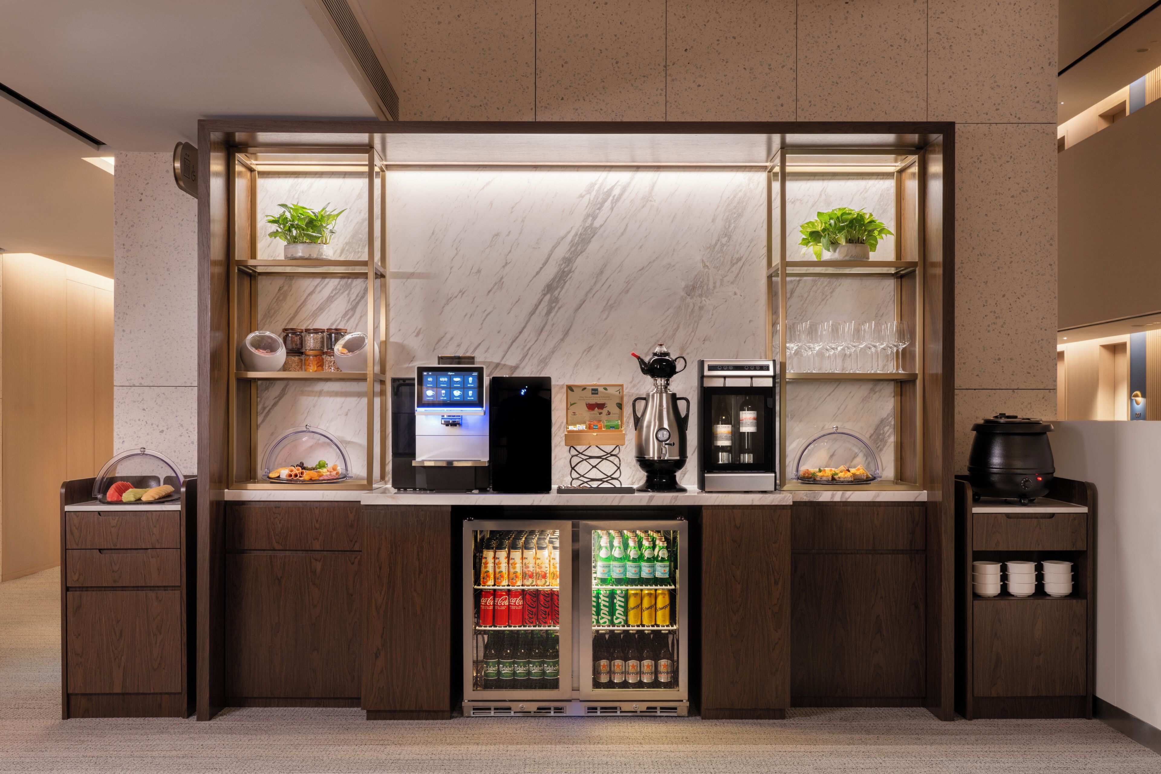 A self-service beverage station with a coffee machine, tea dispenser, and a refrigerated drink cooler.