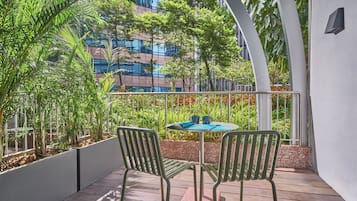 Un balcon avec deux chaises, une table et une vue sur un immeuble et des espaces verts.