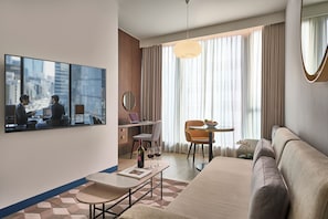 Uma sala de estar moderna com sofá, mesa de jantar, televisão e vista para a cidade.