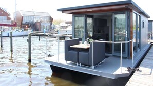 Ein modernes schwimmendes Haus mit Essbereich, Küche und großen Fenstern.