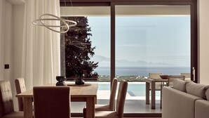 A modern dining area with a view of the sea, a Christmas tree, and a large window. - Julieta Villas (Zakynthos)