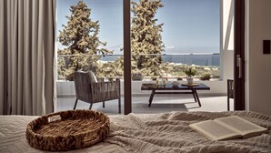 A bedroom with a large window overlooking a balcony with a view of trees and the sea. - Julieta Villas (Zakynthos)