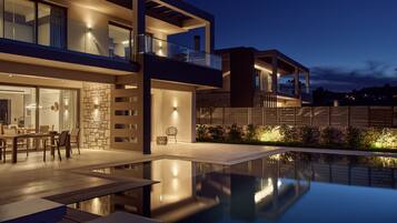 A modern two-story house with a swimming pool, outdoor seating, and a stone wall.