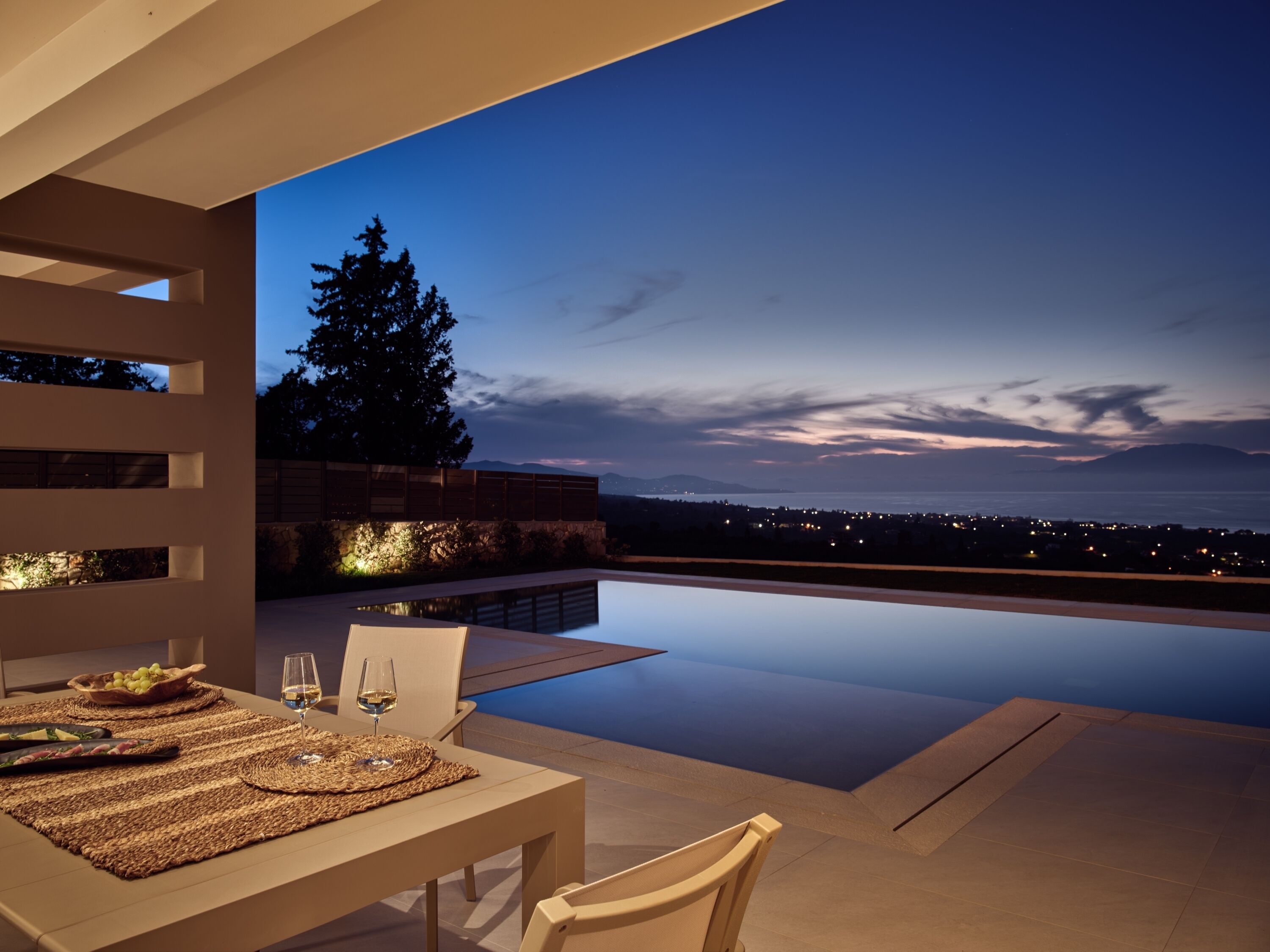 A modern outdoor dining area with a view of the city at dusk.