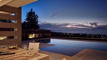 A modern outdoor dining area with a view of the city at dusk.