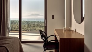A modern hotel room with a large sliding glass door leading to a balcony with a view of a distant mountain and landscape. - Julieta Villas (Zakynthos)