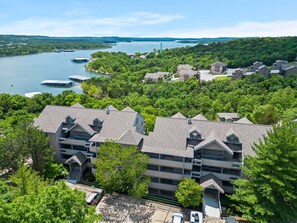 A multi-story hotel with a central courtyard, surrounded by lush greenery and a lake with boats.