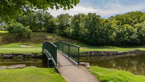 A green bridge over a pond with a golf course in the background. - Romantic Getaway Near Silver Dollar City with Free Tickets & Onsite Golf Course (Reeds Spring)