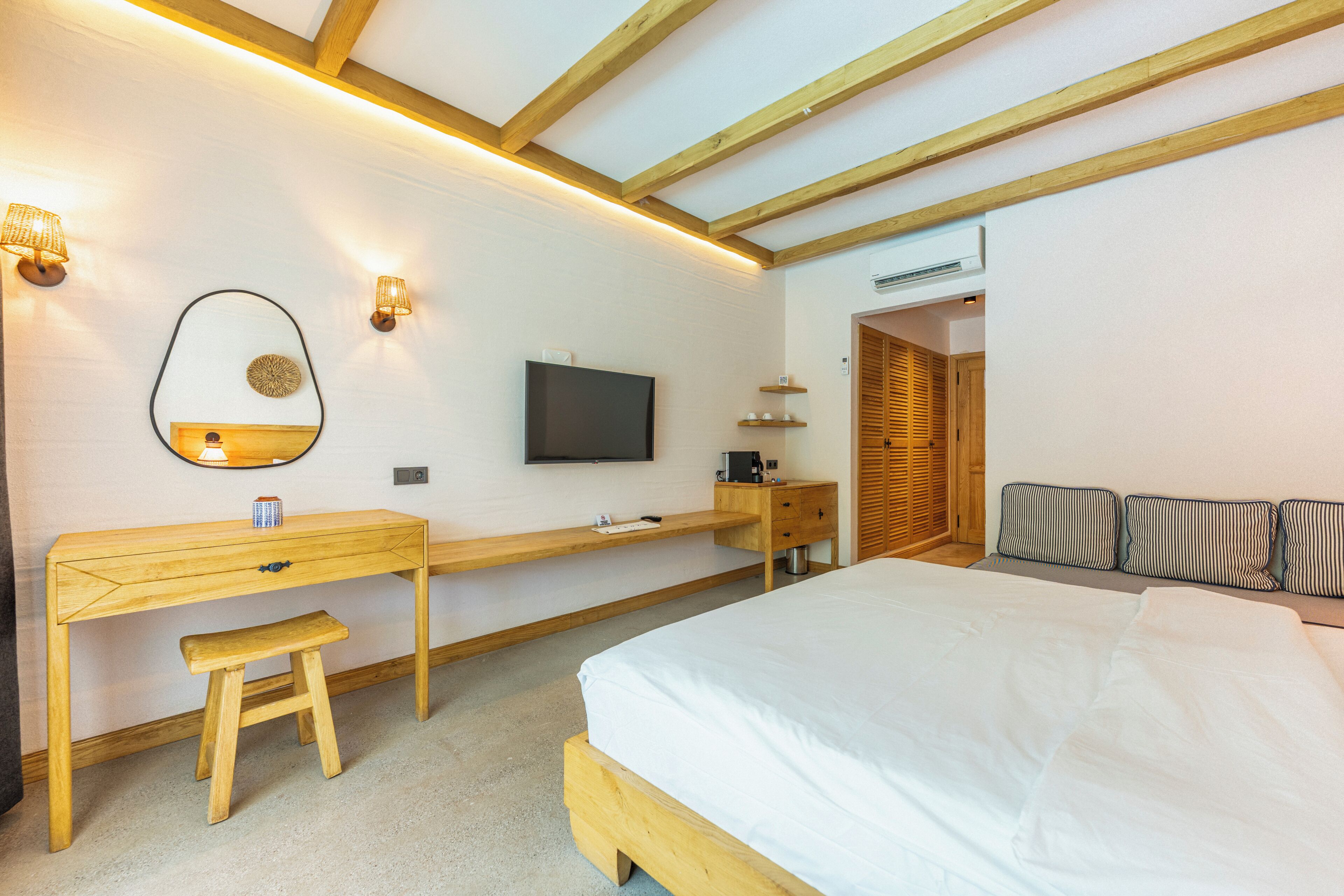 A bedroom with a bed, a desk, a chair, a TV, and a mirror.