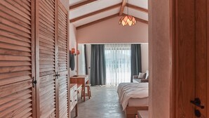 A bedroom with a wooden wardrobe, a desk, a bed, and a hanging light fixture. - The Pearl Ölüdeniz (Fethiye)