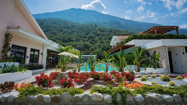A resort with a pool, lush gardens, and a mountainous backdrop. - The Pearl Ölüdeniz (Fethiye)