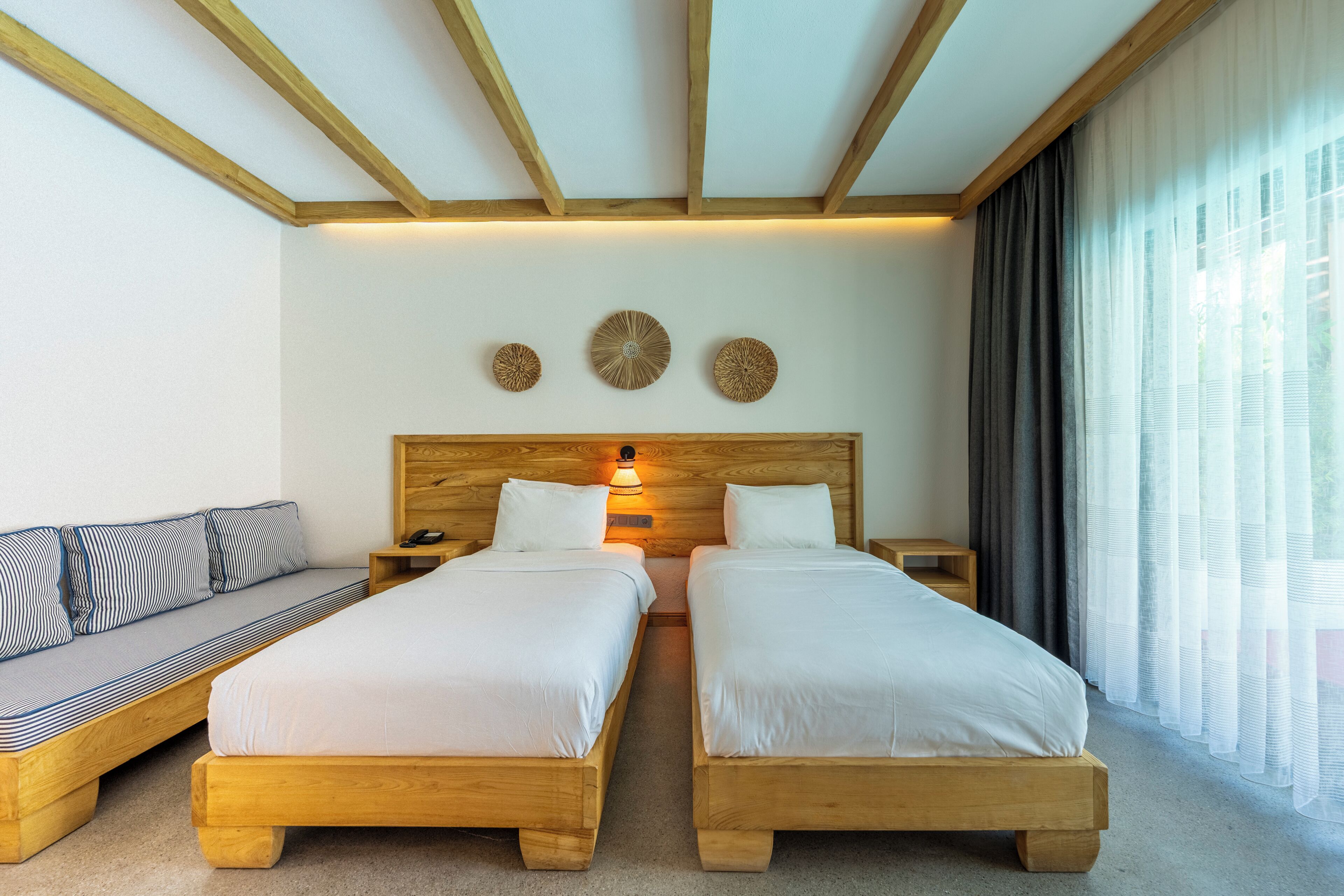 A room with two wooden beds, a sofa, a nightstand with a lamp, and a wall with three circular wall art pieces.