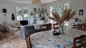 A cozy living room with a dining table, chairs, a TV, and a fireplace. - Large family house, large garden in an oyster site close to the beach (La perrotine)