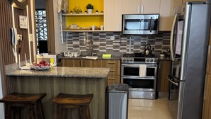 Una cocina moderna con una isla central, electrodomésticos de acero inoxidable y taburetes de madera.