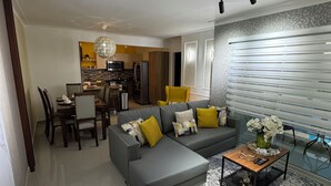 Un salon moderne avec un canapé d’angle gris, une table basse agrémentée d’objets décoratifs et un tapis à motifs.