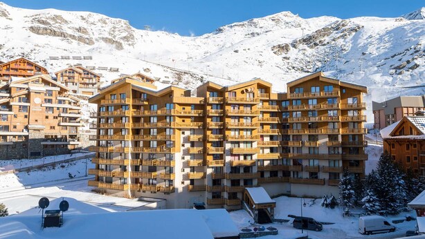 A multi-story hotel with balconies, a ski lift in the background, and snow-covered surroundings. - Charming 2-Bedroom Apartment in Val Thorens - Sleeps 4, Renovated, Ski-In/Ski-Out! (Val Thorens)