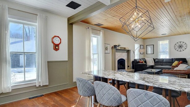 Un salón espacioso con un gran techo de madera, una mesa de comedor de mármol y una chimenea.