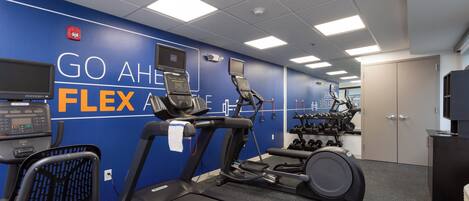 A fitness center with treadmills, elliptical machines, and dumbbells.