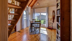 A wooden interior with a dining table and chairs, a staircase, and a view through large windows. - Bears Valley #171 (Sevierville)