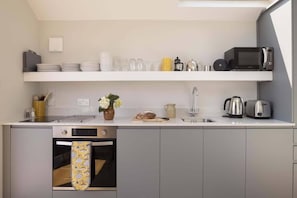 Een moderne keuken met grijze kastjes, een inbouwoven, een magnetron en een spoelbak.