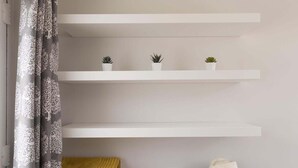 A modern room with white built-in shelves, a white dresser, and a yellow towel. - Stylish Boatshed with Sea Views, Private Parking (Gorran Haven)