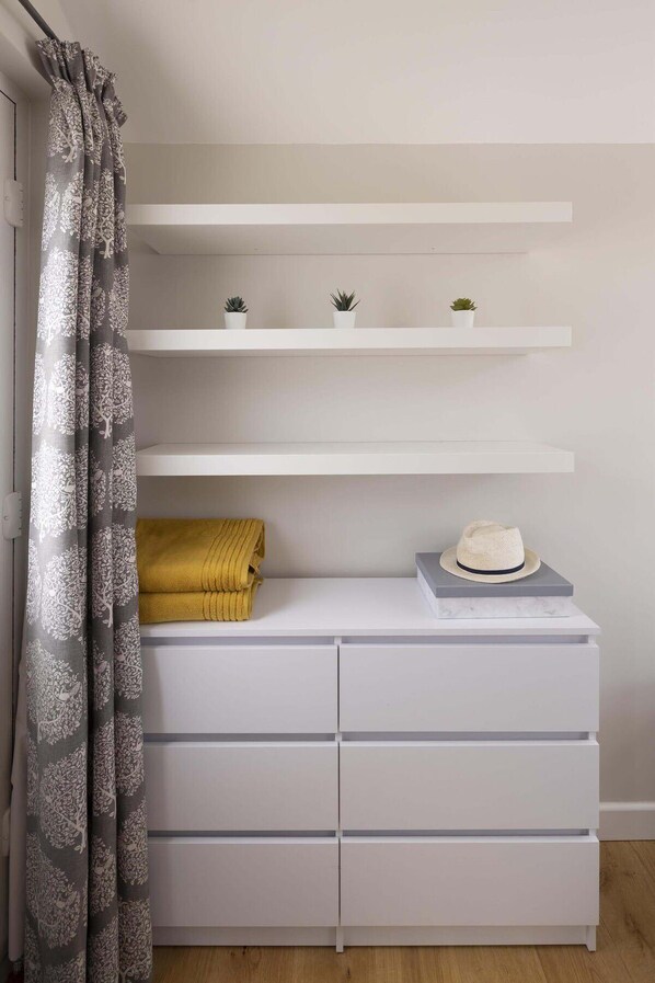 Een moderne kamer met witte inbouwkasten, een witte dressoir en een gele handdoek.