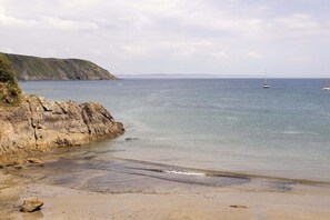 Una playa costera con acantilados rocosos y mar tranquilo.